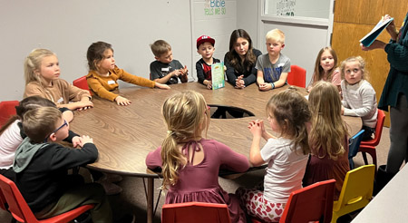 children at a round table listening to a story