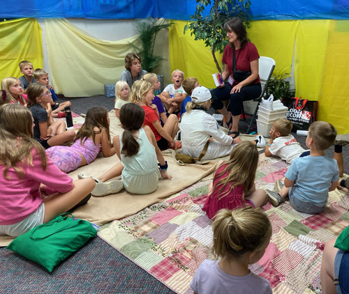 storytime in a setting with blankets and colorful wall hangings